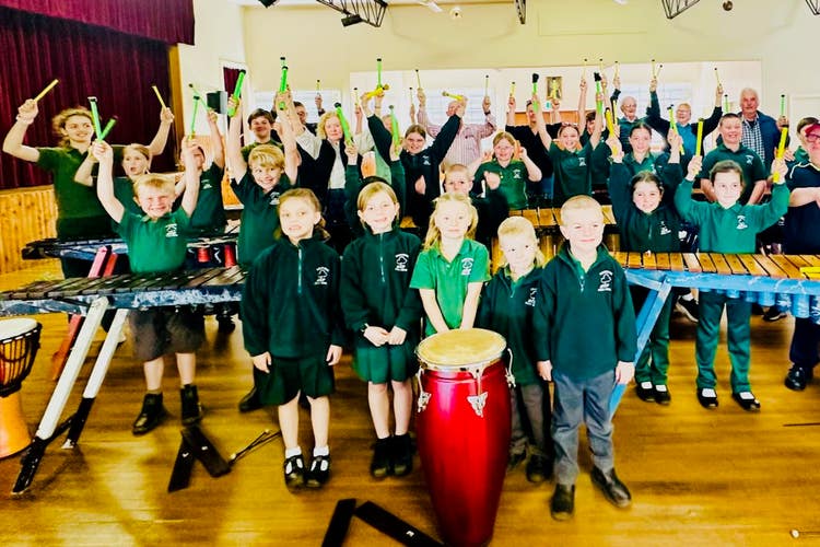 a picture of a group of people standing behind their instruments rasing their hands in the air