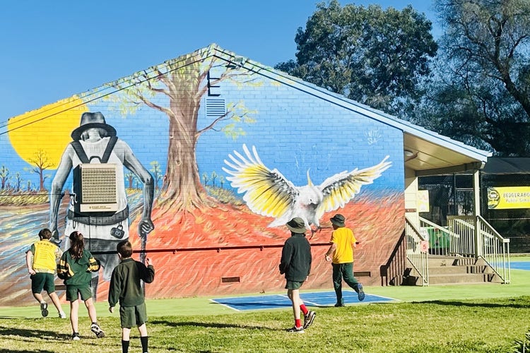 a picture of several students in front of a colourful mural including a cockatoo and swagman